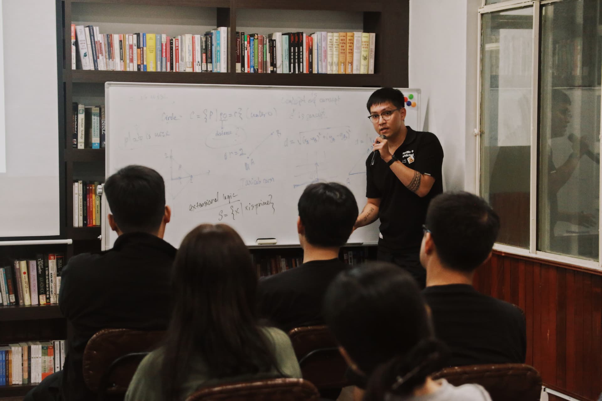 Diễn giả giảng bên bảng trắng kín chữ trước cử tọa.